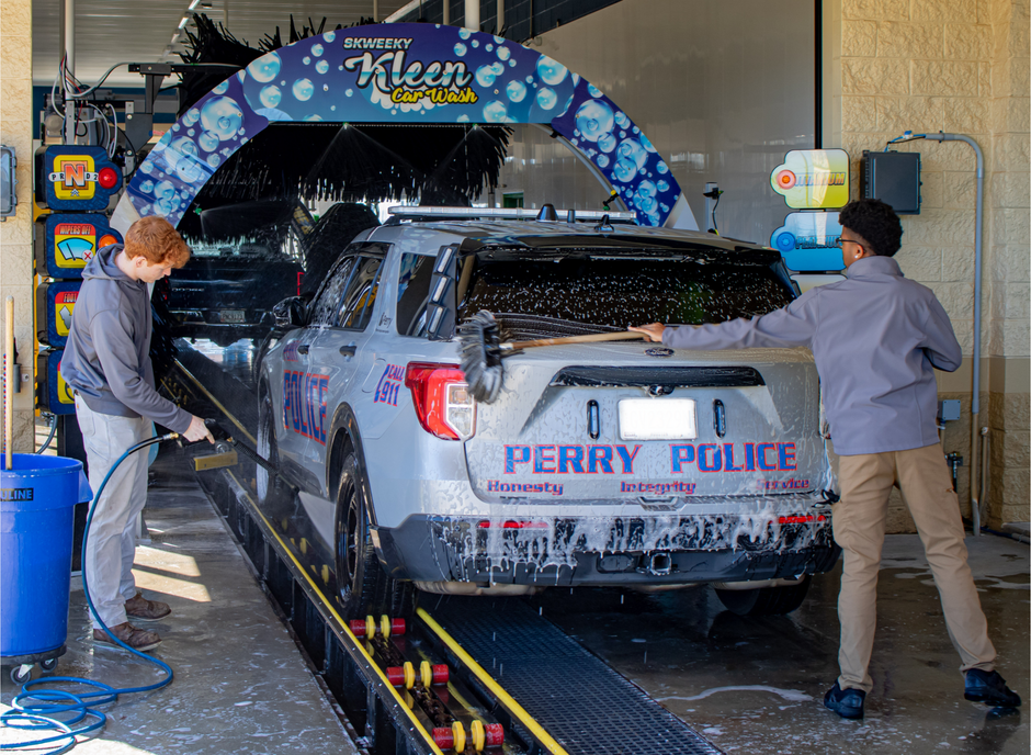 A perry police car is being washed at a car wash.