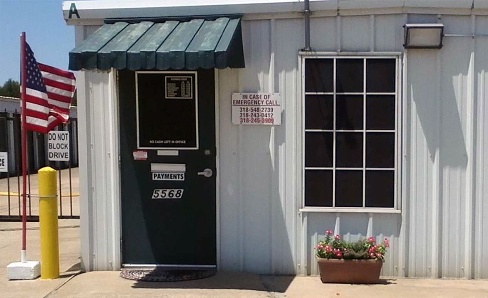 A white building with a green door and an american flag