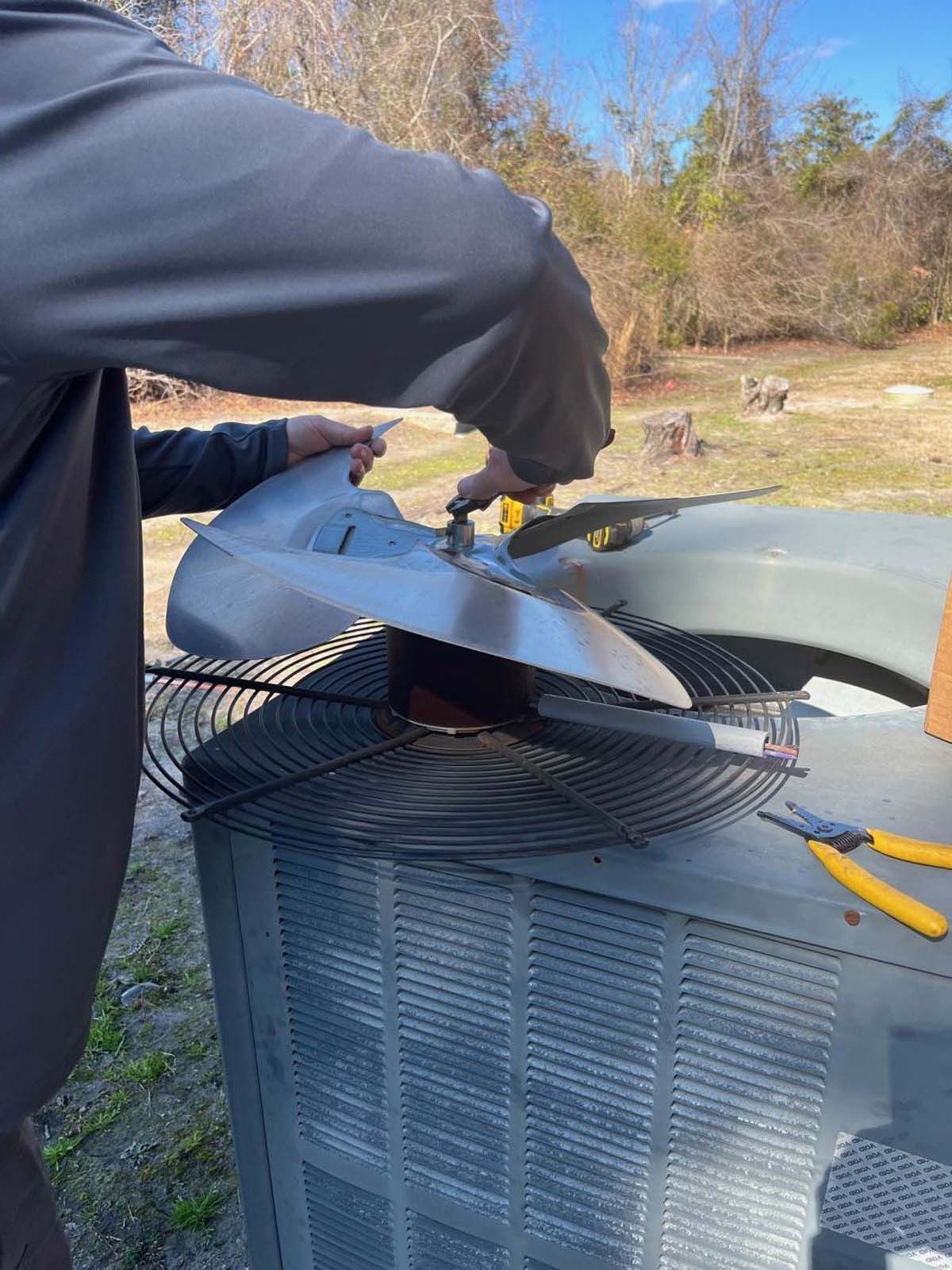 A man is fixing an air conditioner with a pair of pliers.