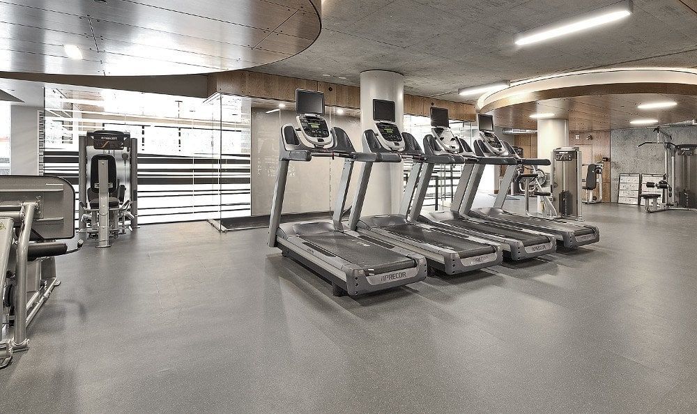 Interior view of a modern fitness center with four treadmills and cardio machines.