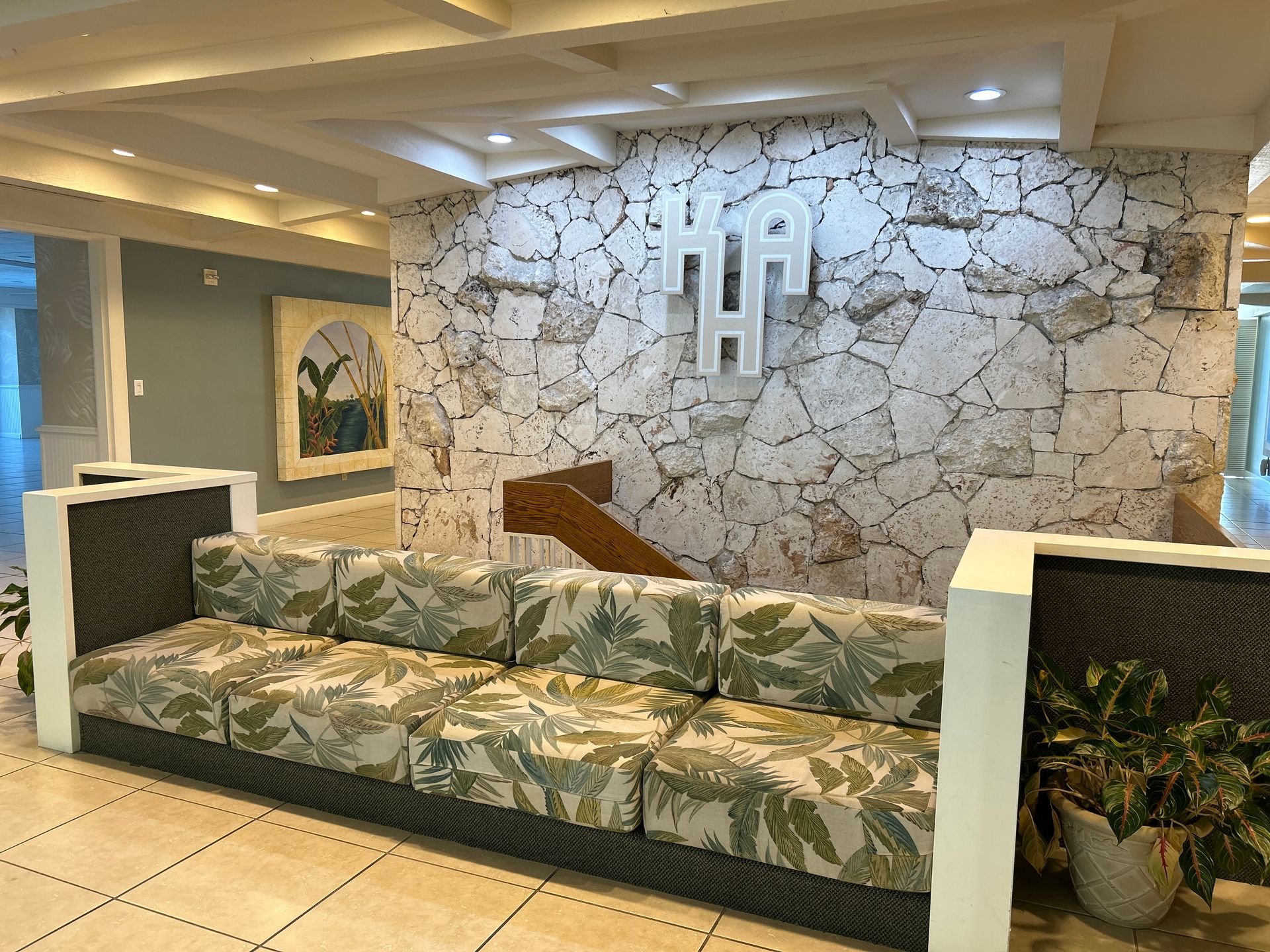 A couch is sitting in front of a stone wall in a lobby.
