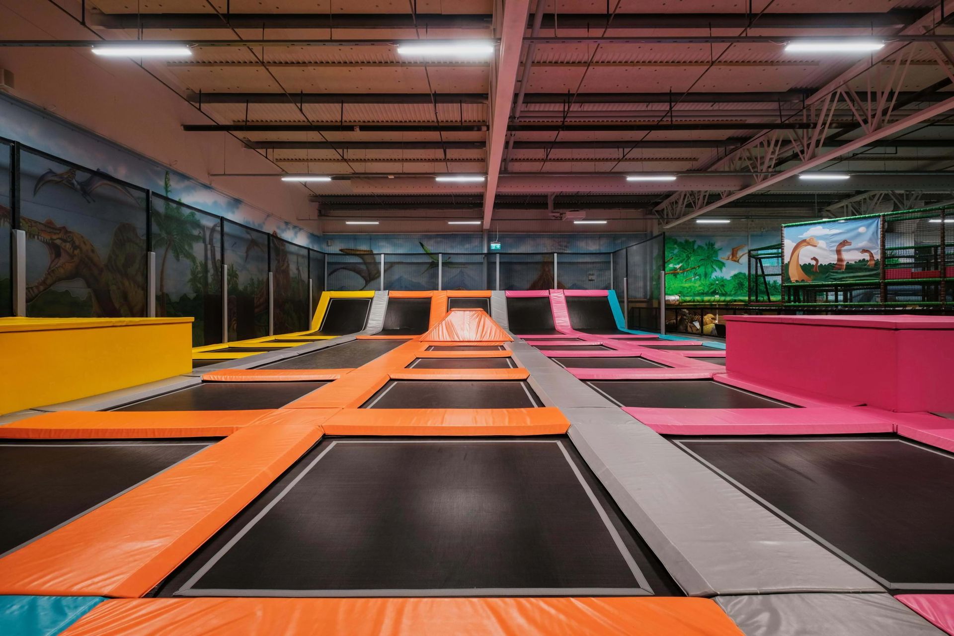 Indoor trampoline park with colorful trampolines and padding.