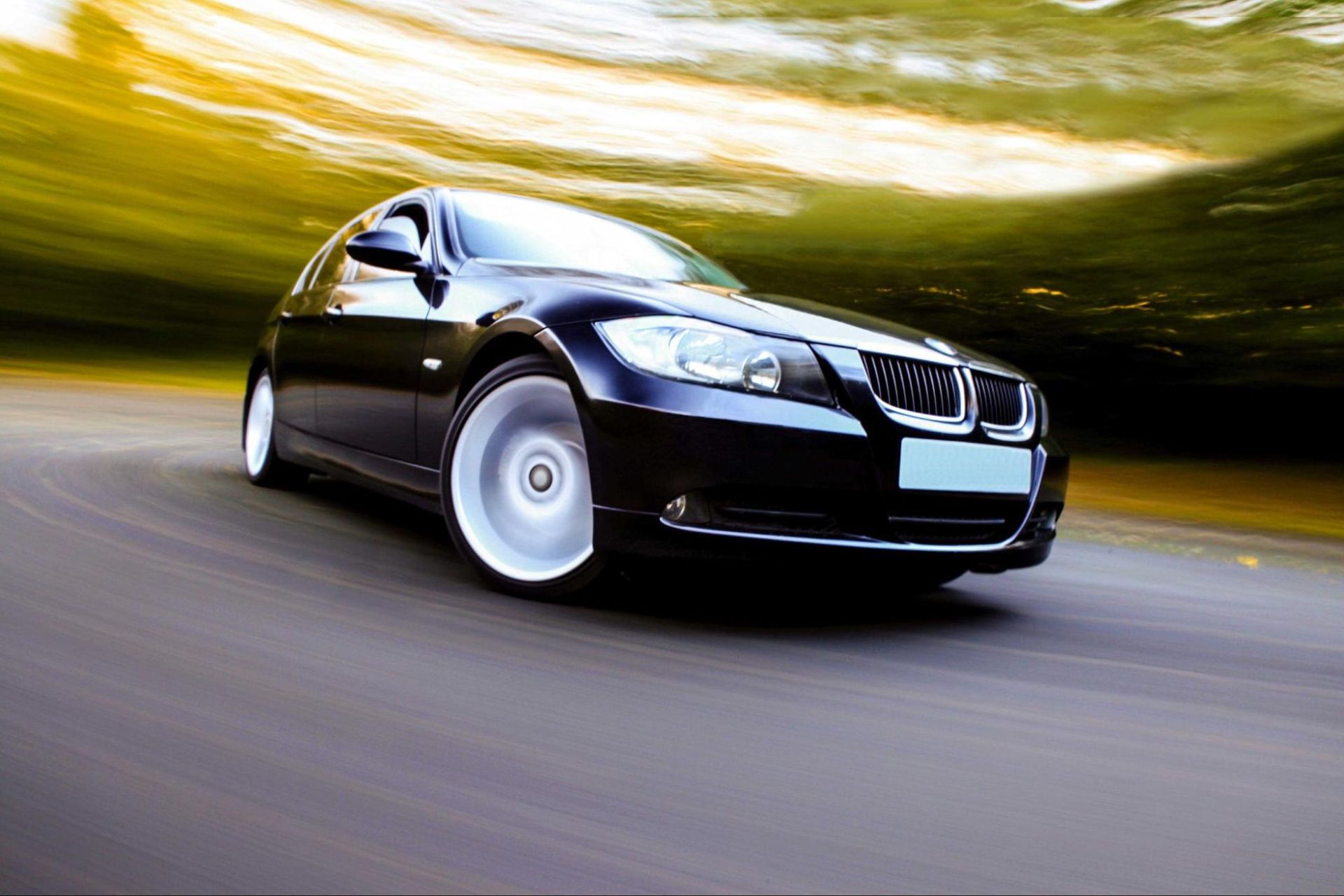 A black car is driving down a road with a blurry background.