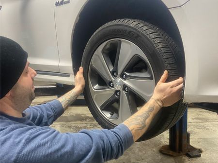 A man is adjusting a tire on a car on a lift.