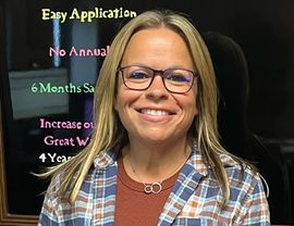 A woman wearing glasses and a plaid shirt is smiling in front of a sign that says easy application.