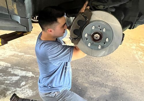 A man is working on the brake rotor of a car.