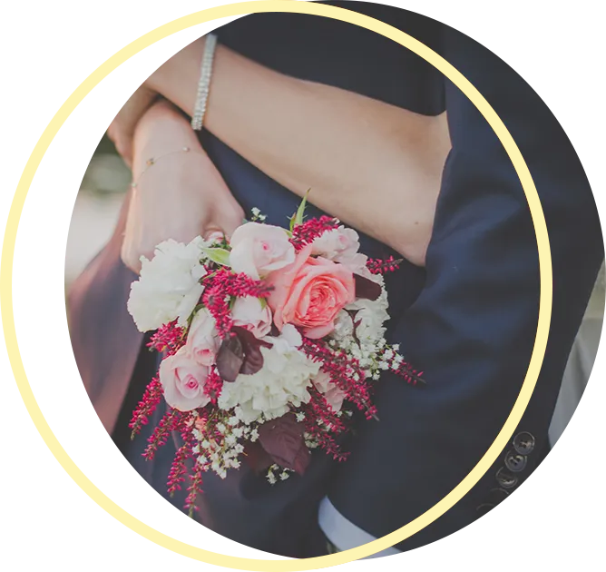 A bride and groom are hugging and the bride is holding a bouquet of flowers.