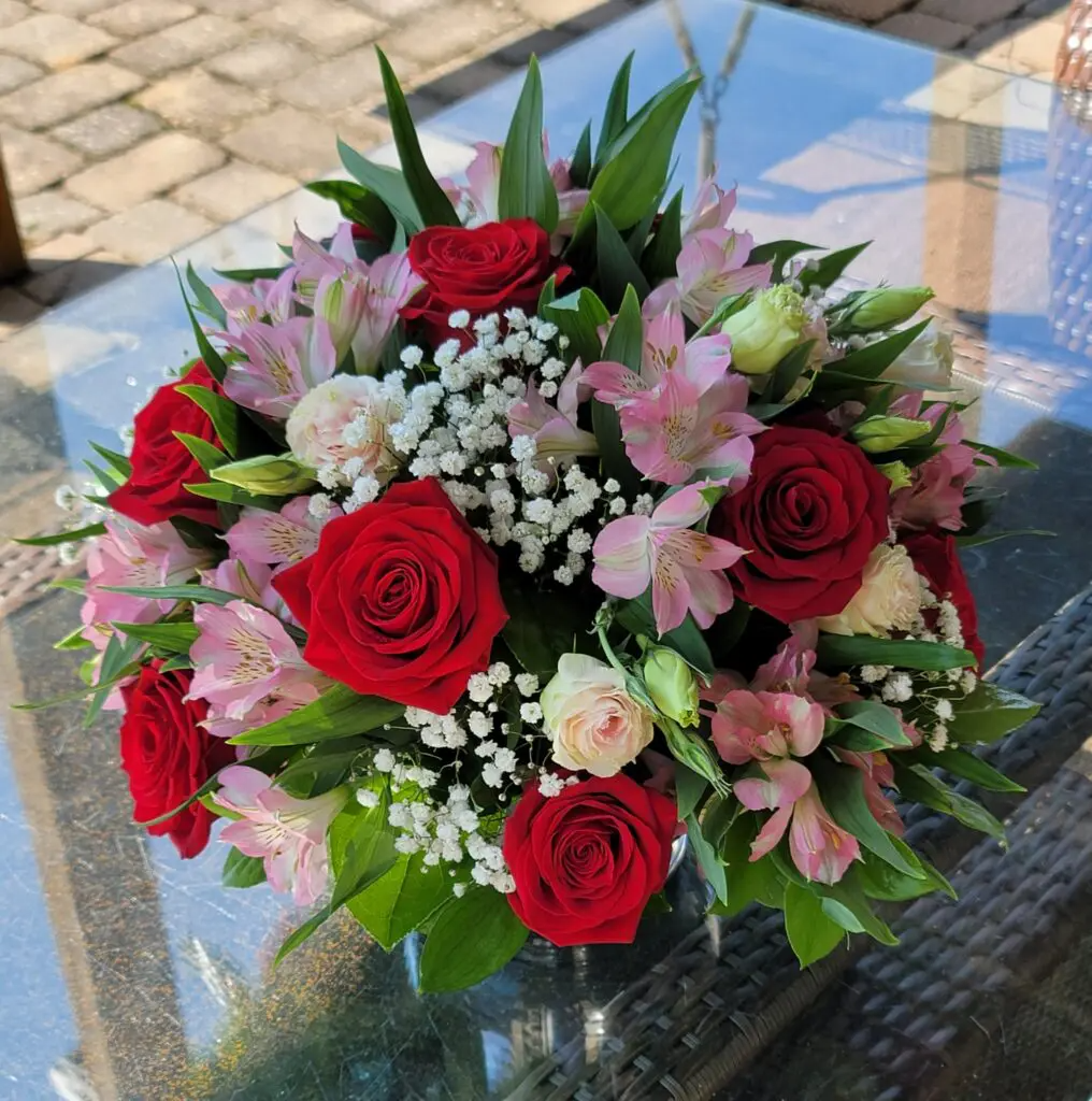 A bouquet of red roses and pink flowers on a table