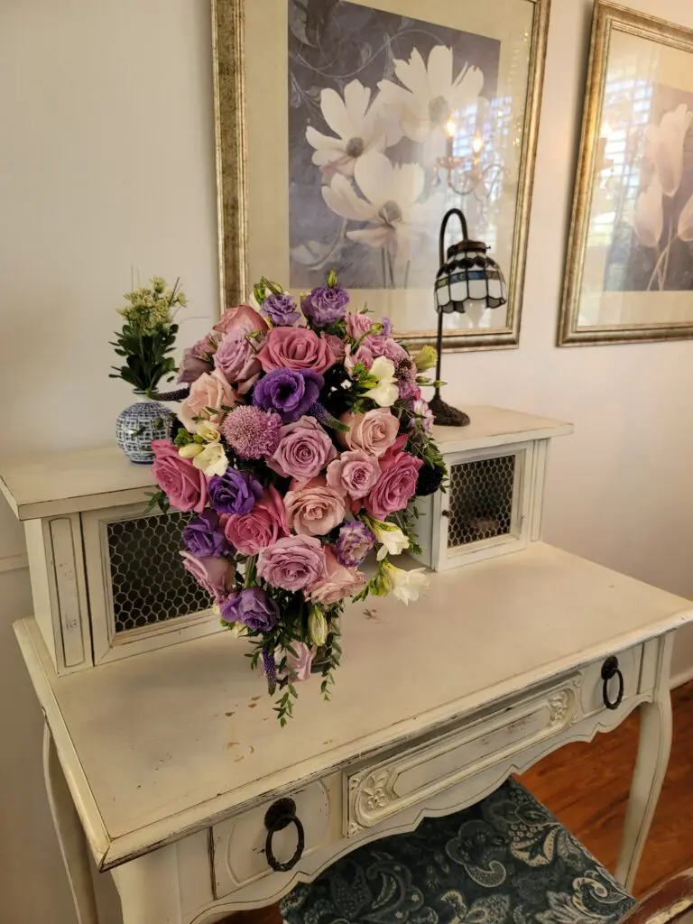 A bouquet of pink and purple flowers is sitting on a white table.