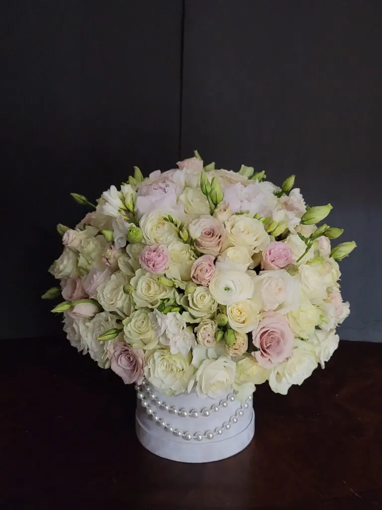 A white box filled with white and pink flowers and pearls.