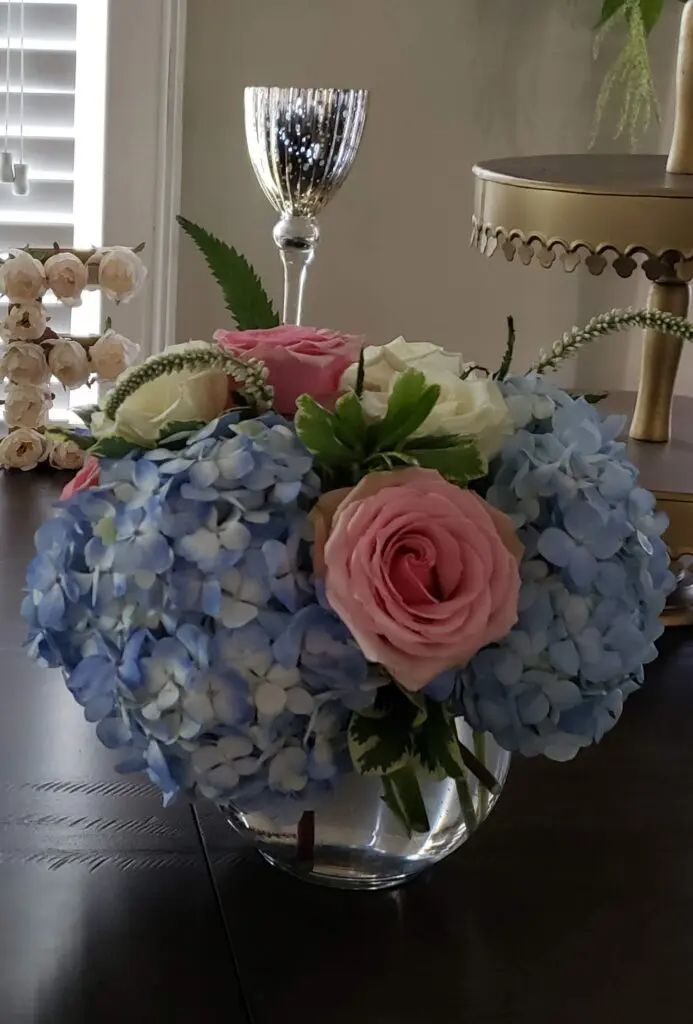 A vase filled with blue and pink flowers is on a table.