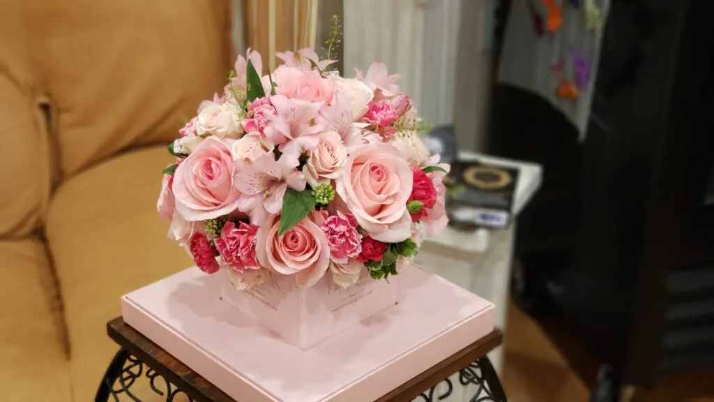 A bouquet of pink flowers is sitting on top of a pink box on a table.
