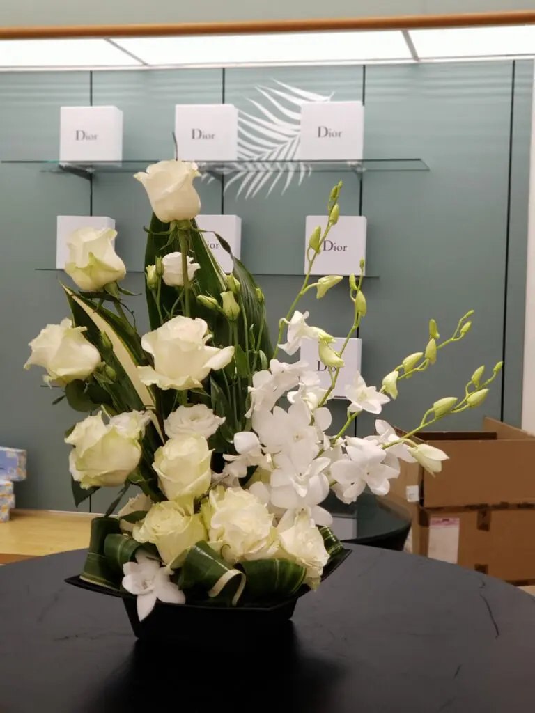 A vase filled with white flowers sits on a table