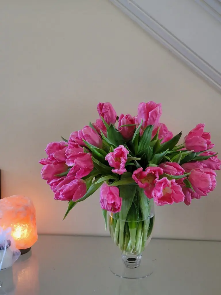 A vase filled with pink tulips is sitting on a table.