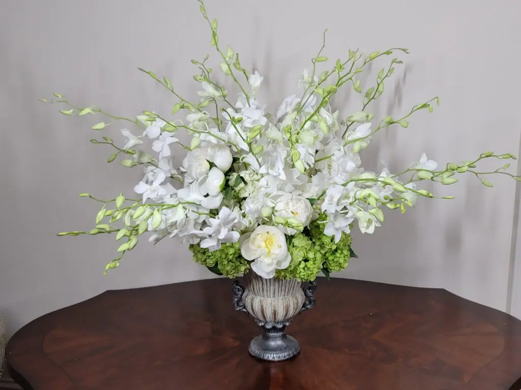 A vase filled with white flowers is sitting on a wooden table.