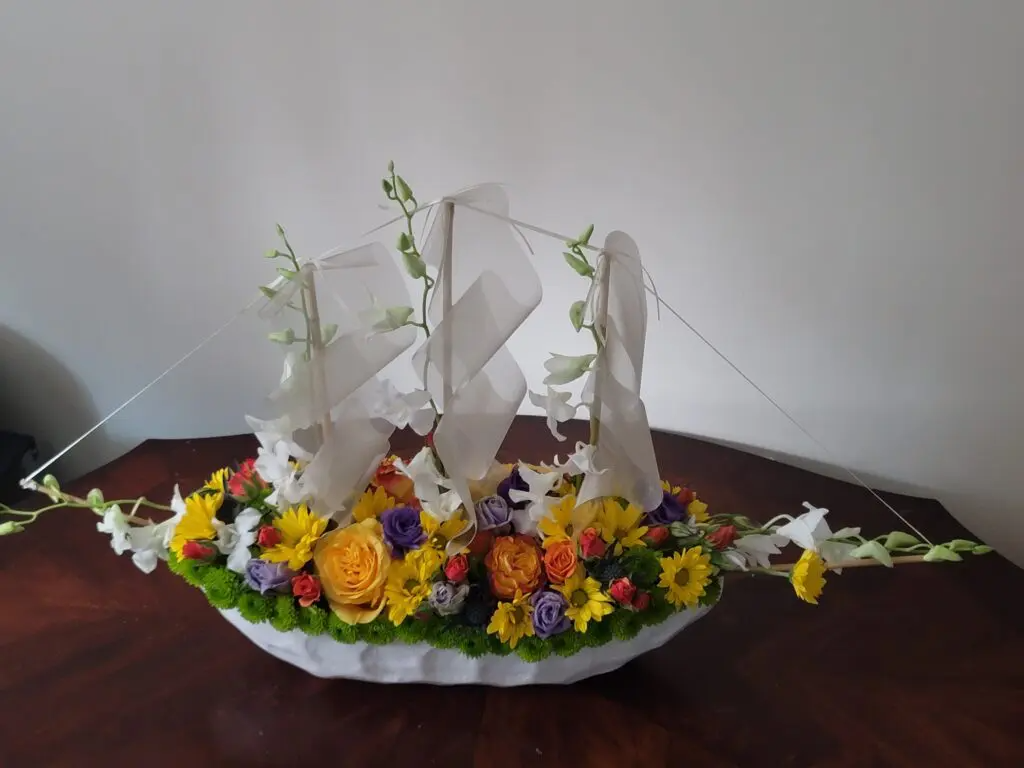 A flower arrangement in the shape of a sailboat on a table