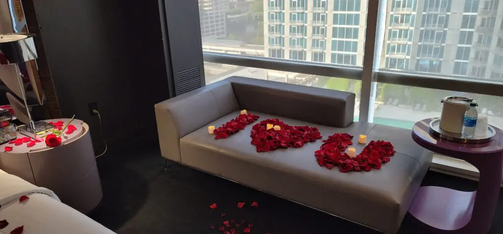A couch in a hotel room decorated with roses and candles.