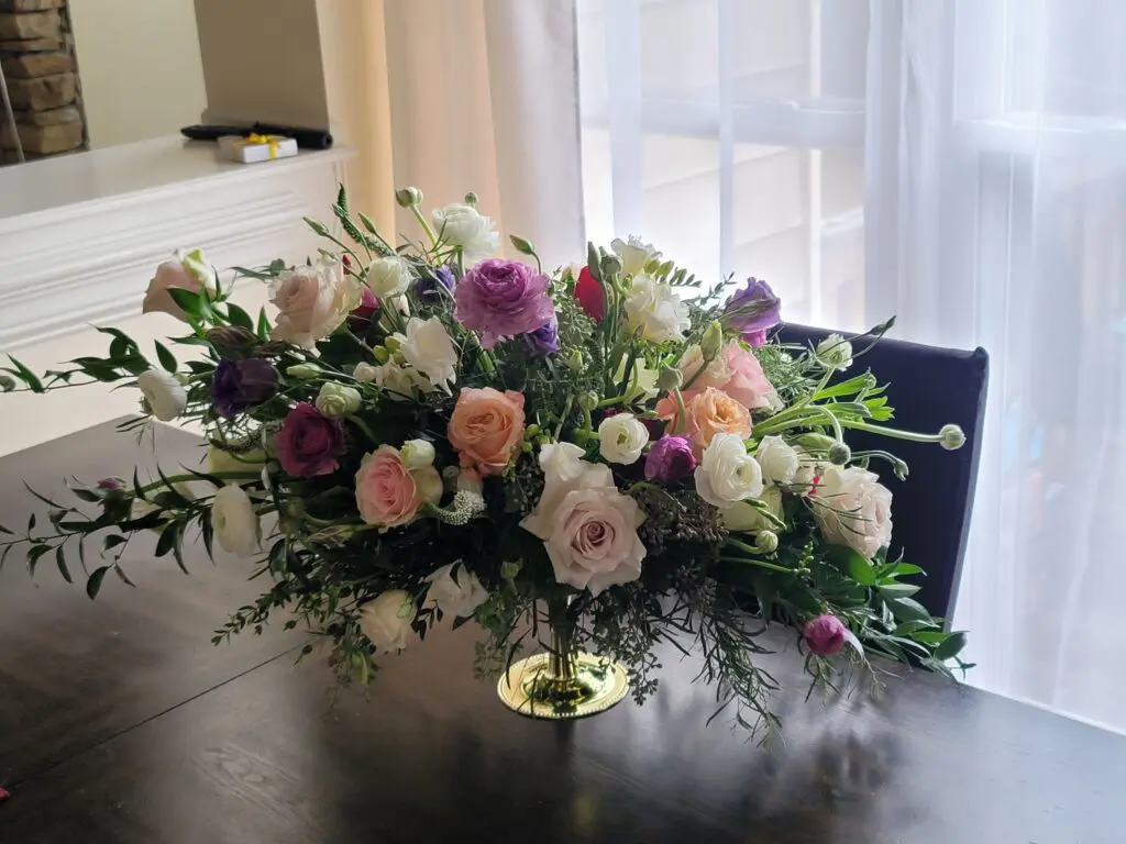 A vase filled with flowers is sitting on a table in front of a window.