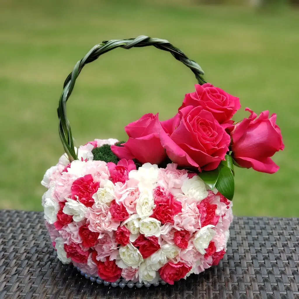 A basket filled with pink and white flowers is sitting on a table.