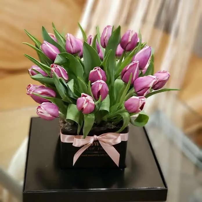 Purple tulips in a black box with a pink bow