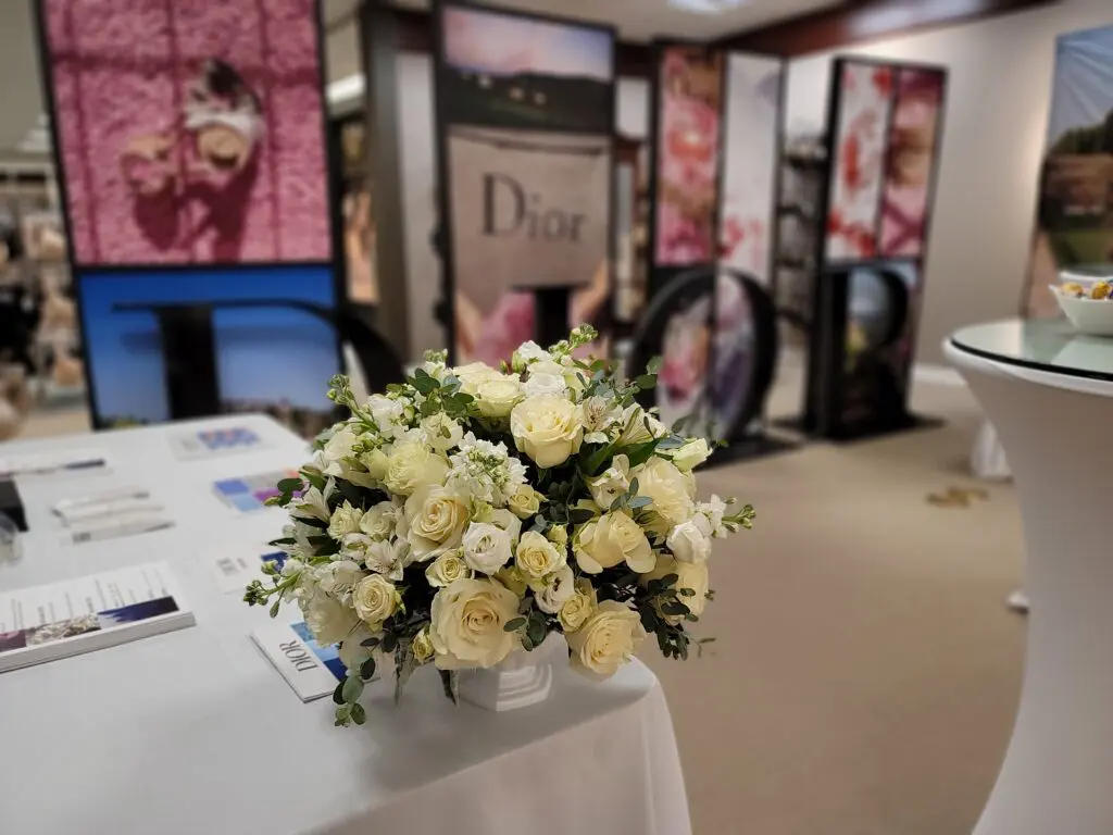 A bouquet of white roses is sitting on a table in front of a dior sign.