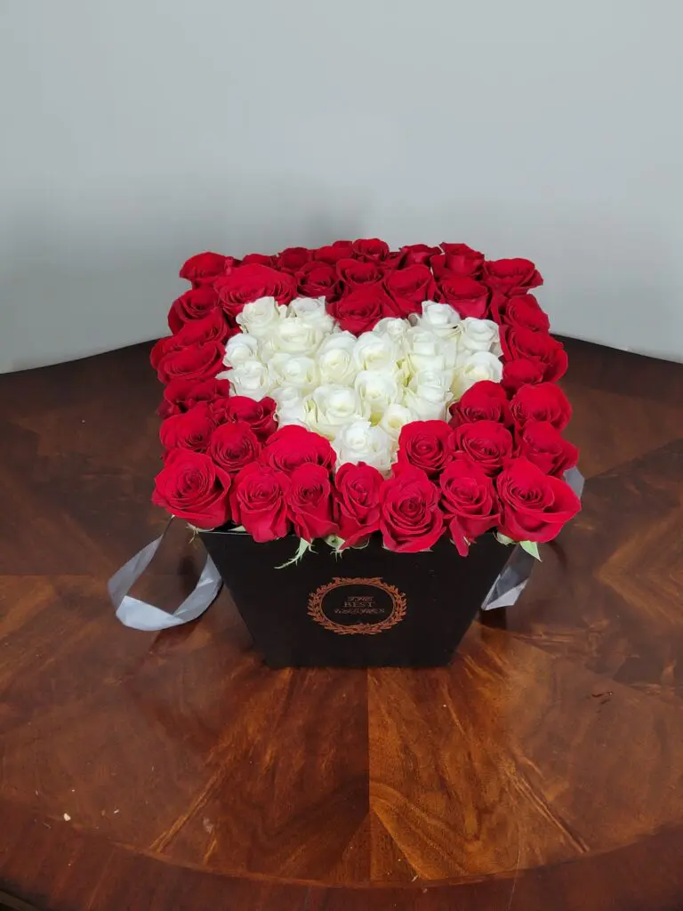 A black box filled with red and white roses in the shape of a heart.