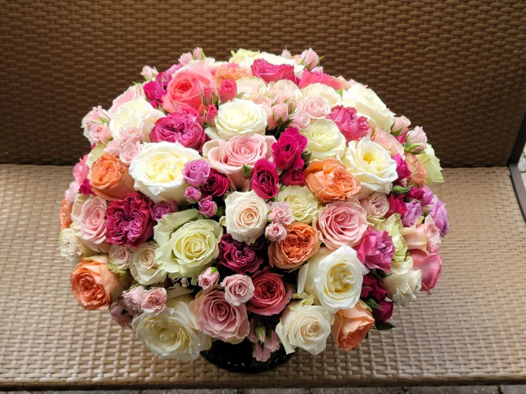 A vase filled with lots of different colored roses is sitting on a table.