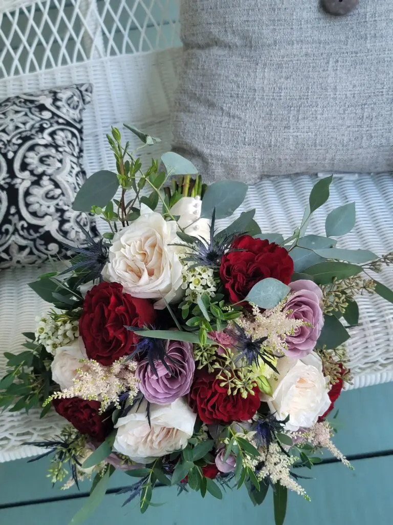 A bouquet of flowers is sitting on a wicker bench.