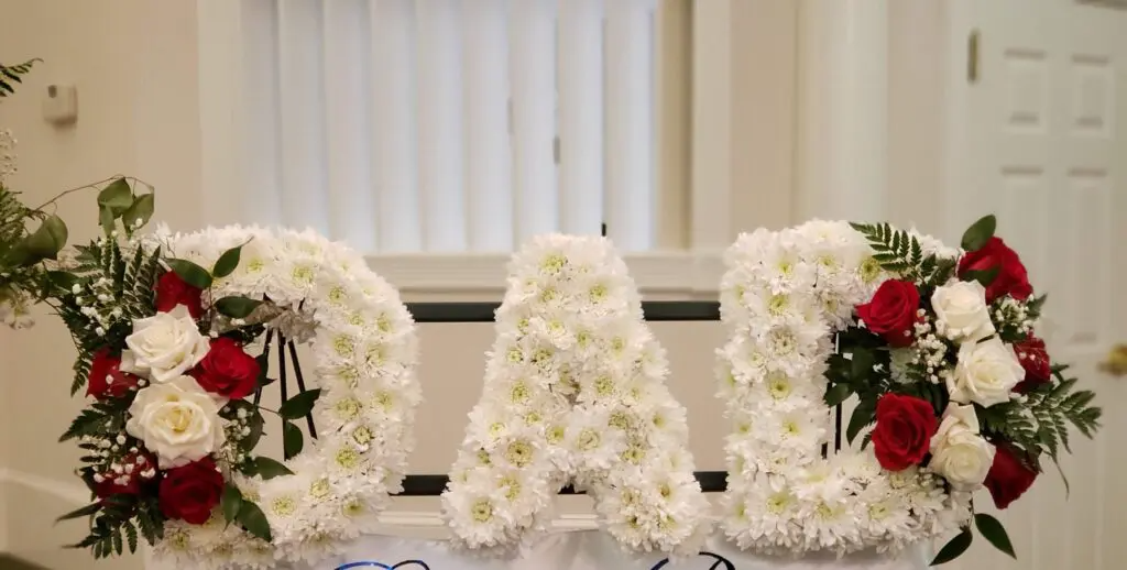 The word dad is made of white flowers and red roses.