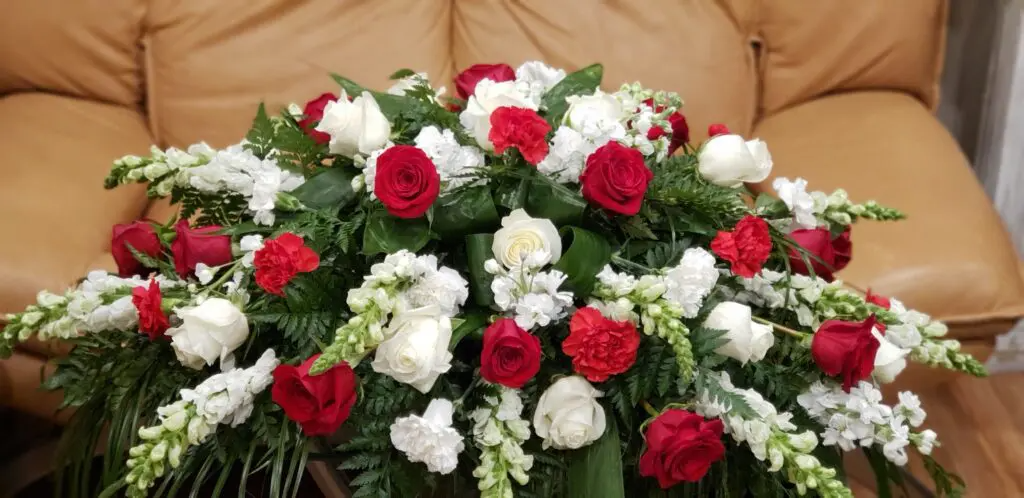 A large bouquet of red and white flowers is sitting on a couch.
