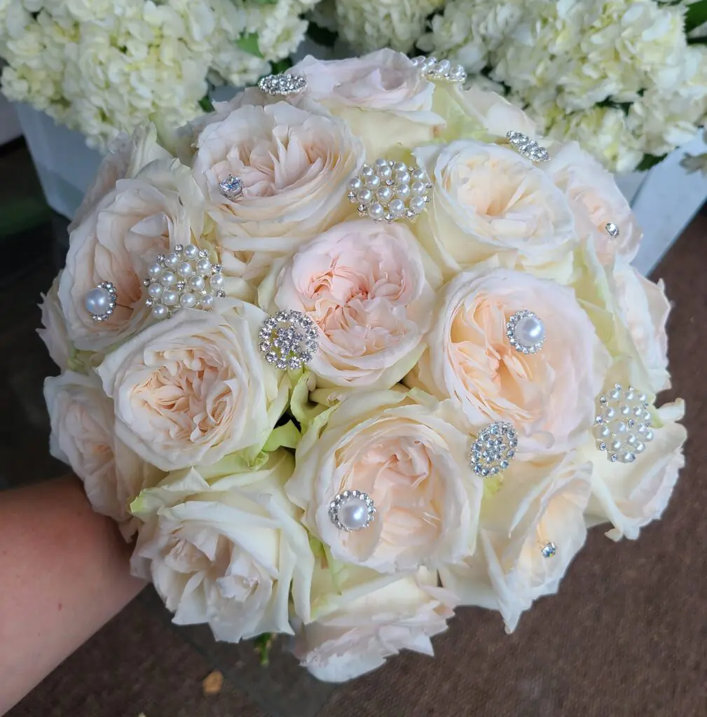 A person is holding a bouquet of white roses and pearls