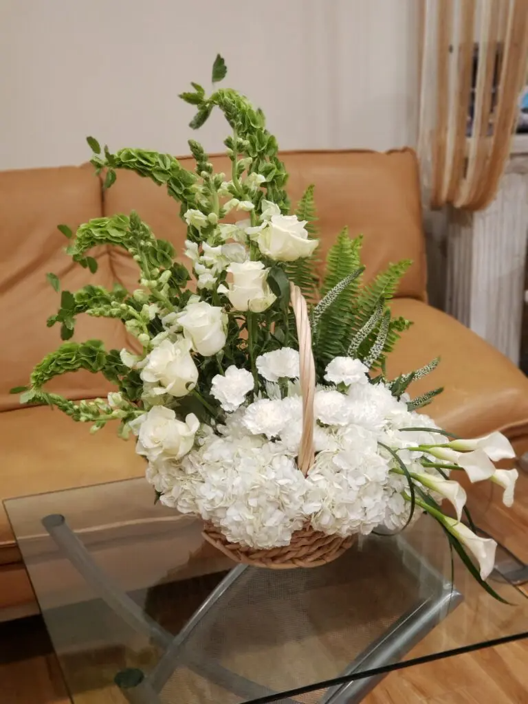 A basket filled with white flowers is sitting on a glass table.