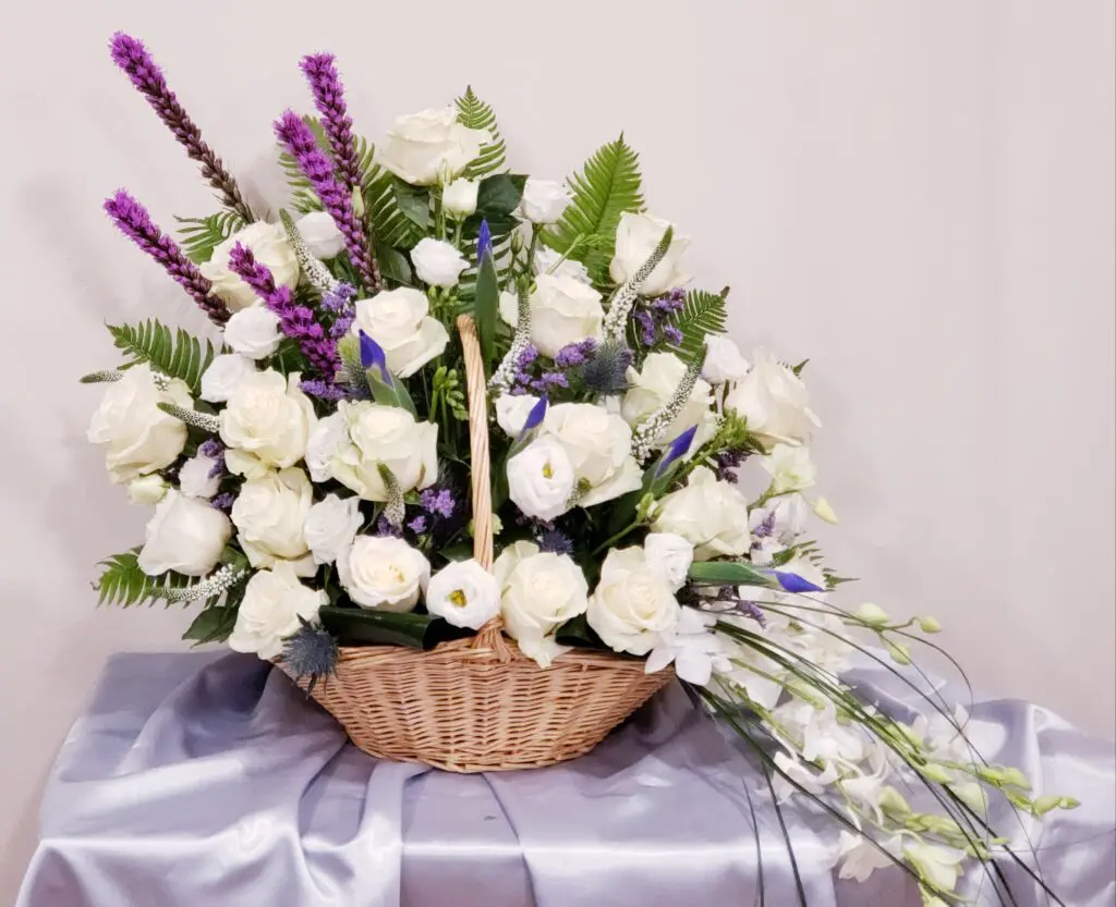A basket filled with white roses and purple flowers