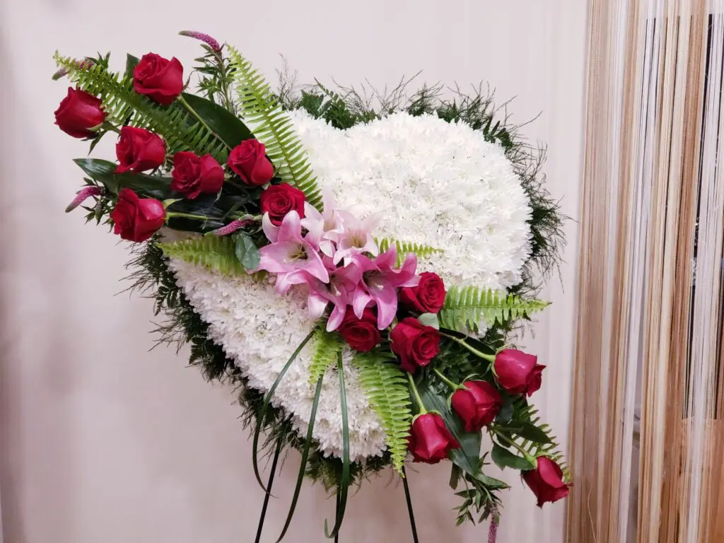 A heart shaped wreath made of white flowers and red roses