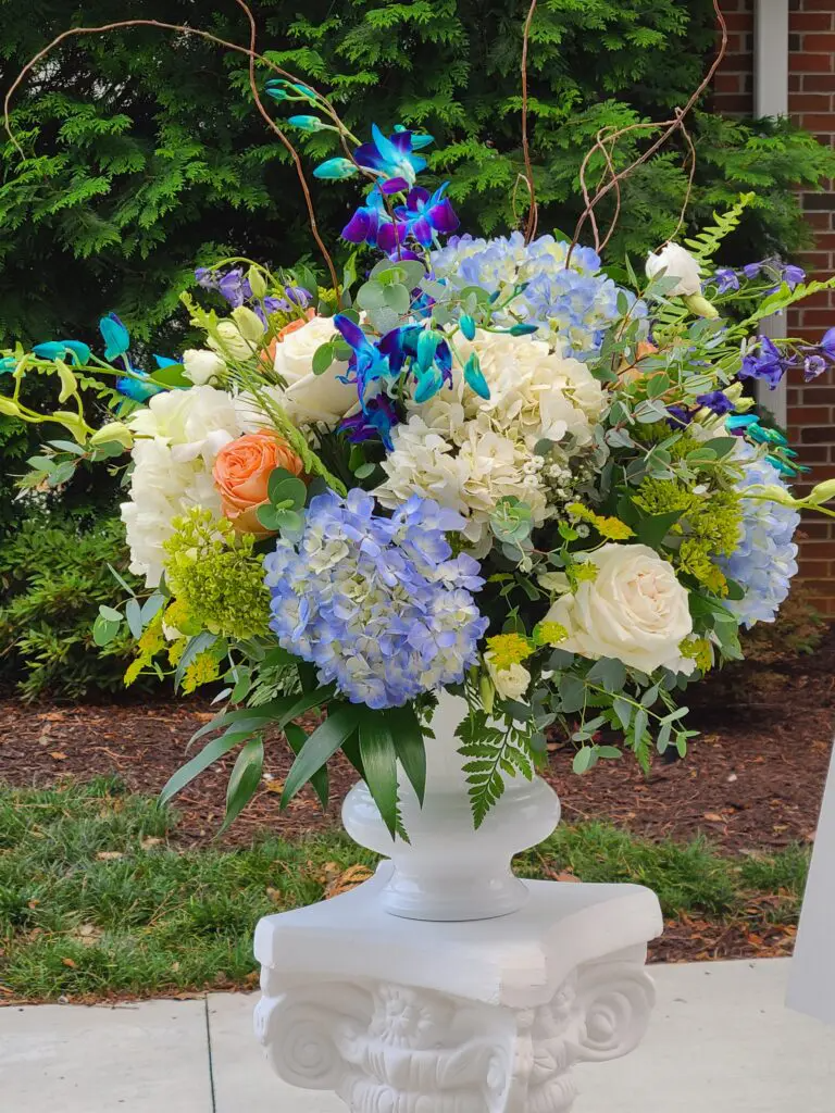 A vase filled with blue and white flowers is sitting on a pedestal.
