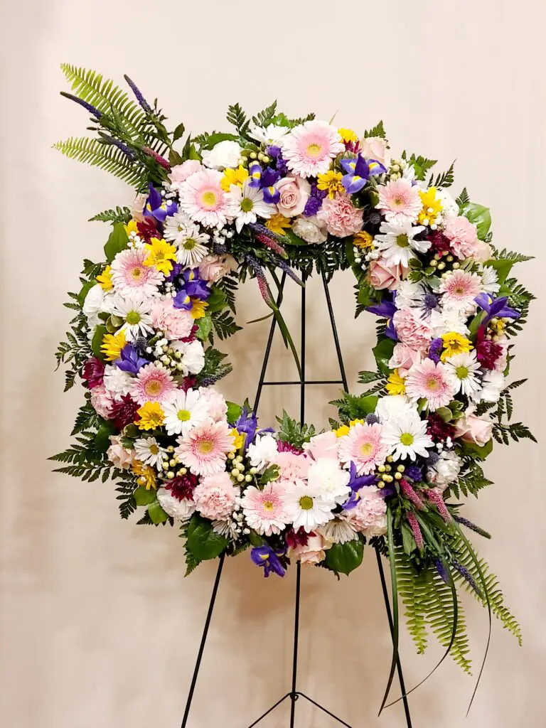 A wreath of flowers is sitting on a metal stand.