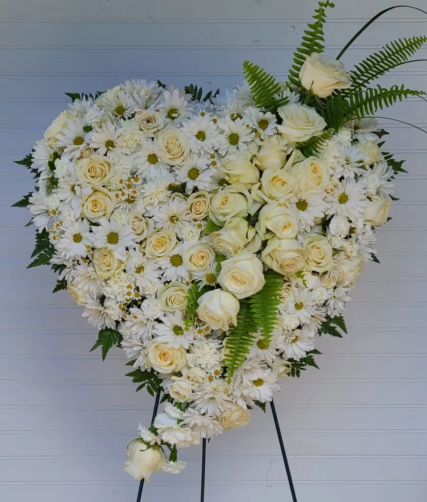 A heart shaped display of white flowers on a stand