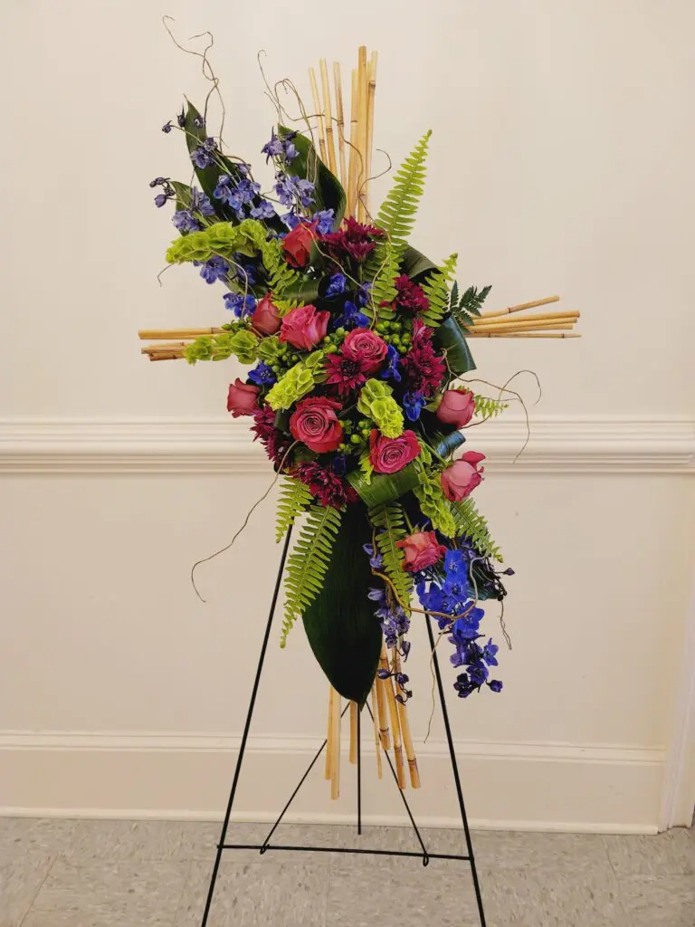 A cross made of flowers is sitting on a stand