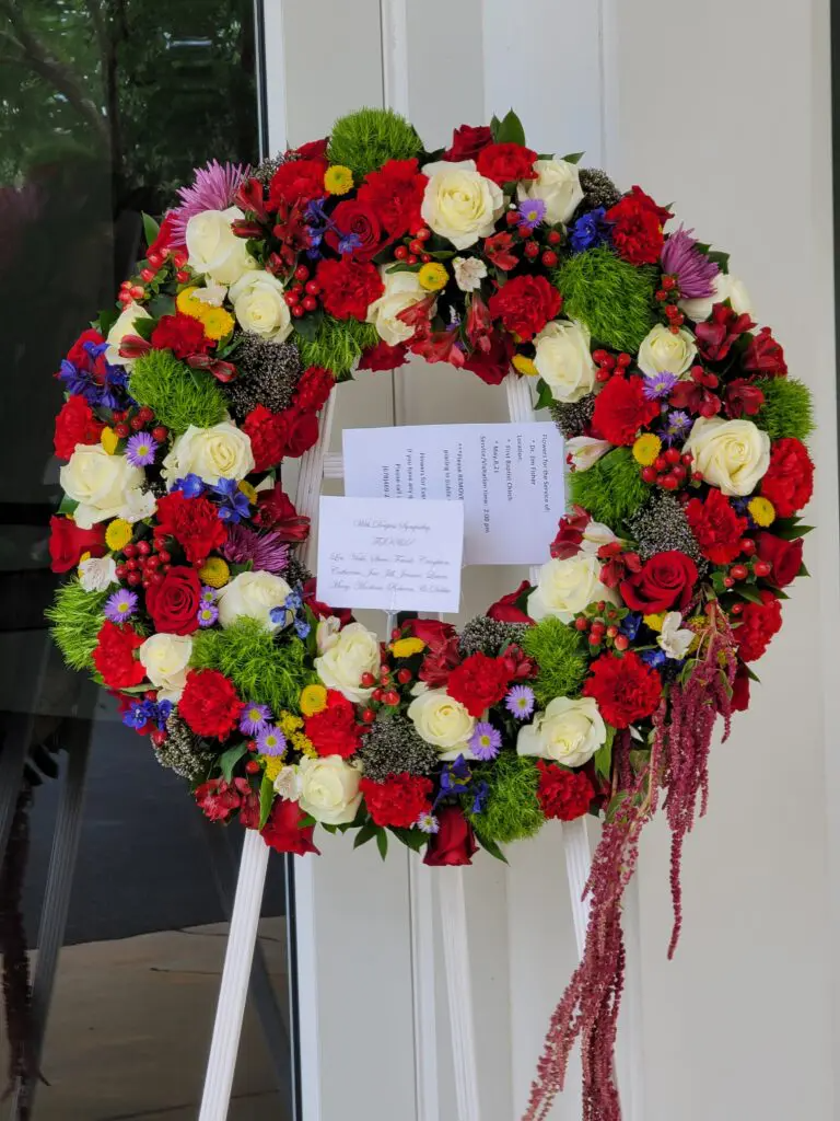 A wreath of red white and green flowers on a stand