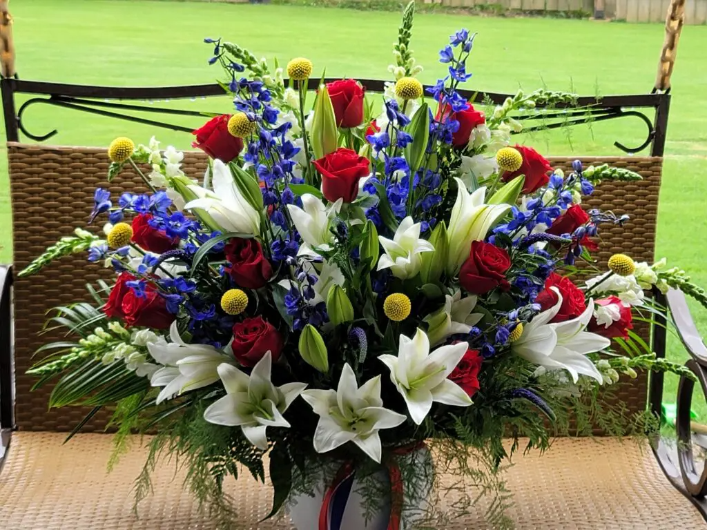 A large bouquet of red , white and blue flowers is sitting on a swing.