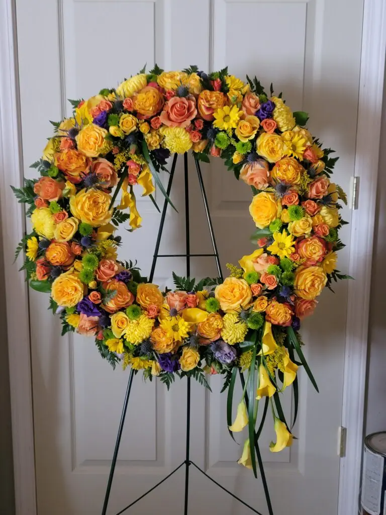 A wreath of yellow and orange flowers on a stand