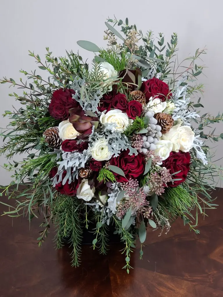 A large bouquet of flowers is sitting on a wooden table.