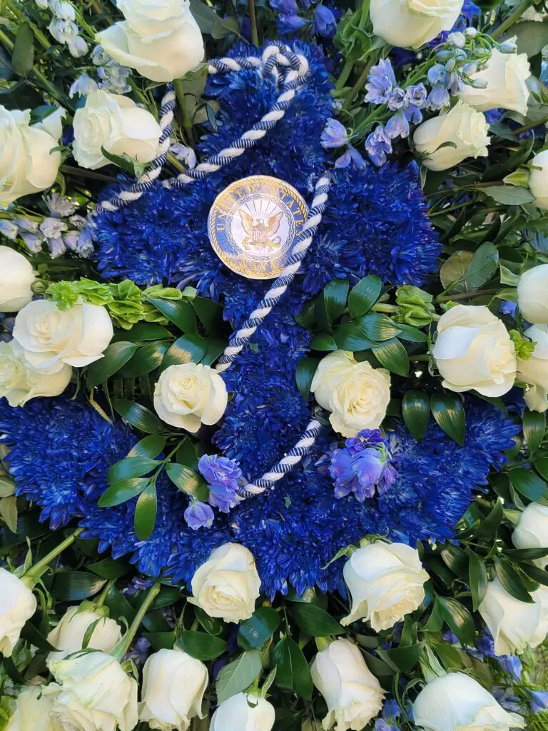 A wreath of blue and white flowers with a medal on top.