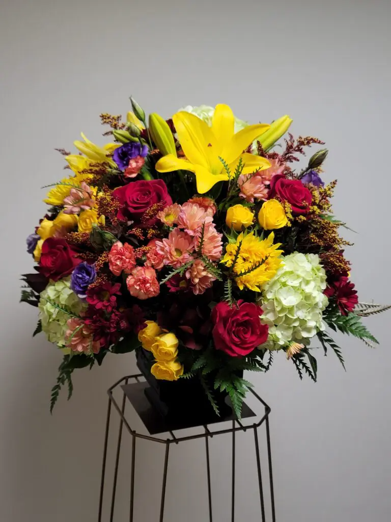 A large bouquet of flowers is sitting on a metal stand.