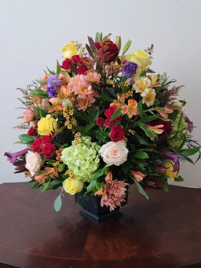 A vase filled with lots of flowers is sitting on a table.