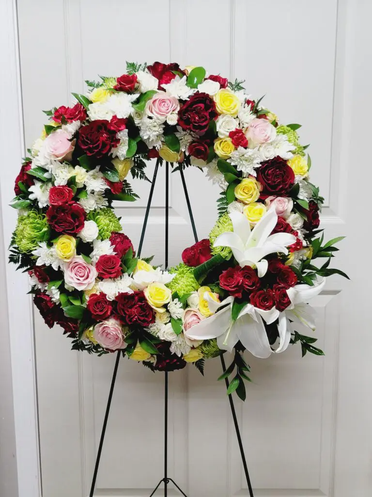 A wreath of flowers is sitting on a stand in front of a door.