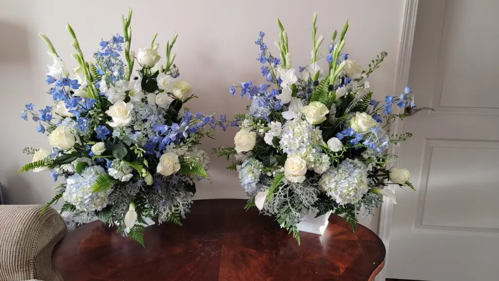Two vases filled with white and blue flowers are sitting on a table.
