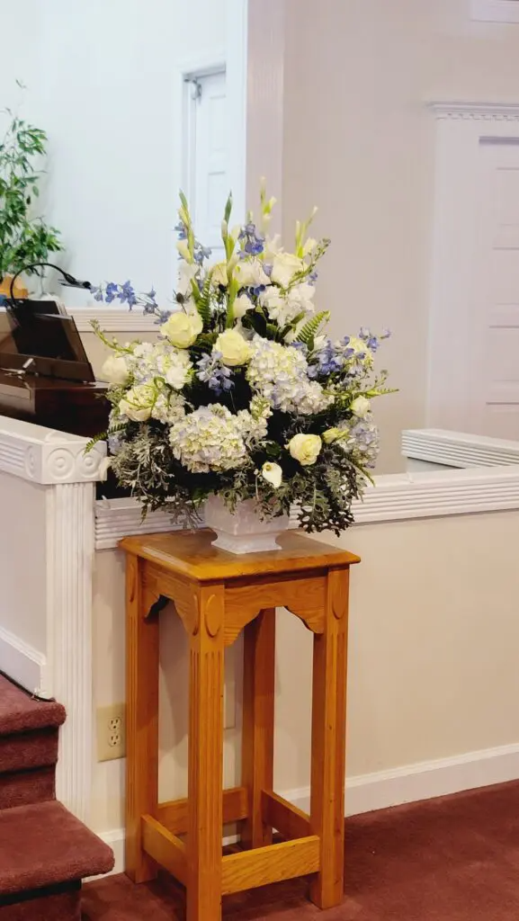 A vase of flowers is sitting on a wooden table in a room.