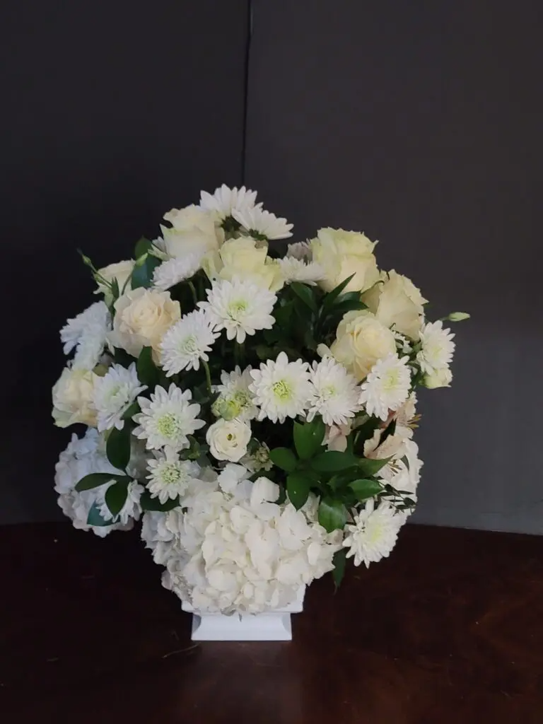 A vase filled with white flowers is sitting on a table.