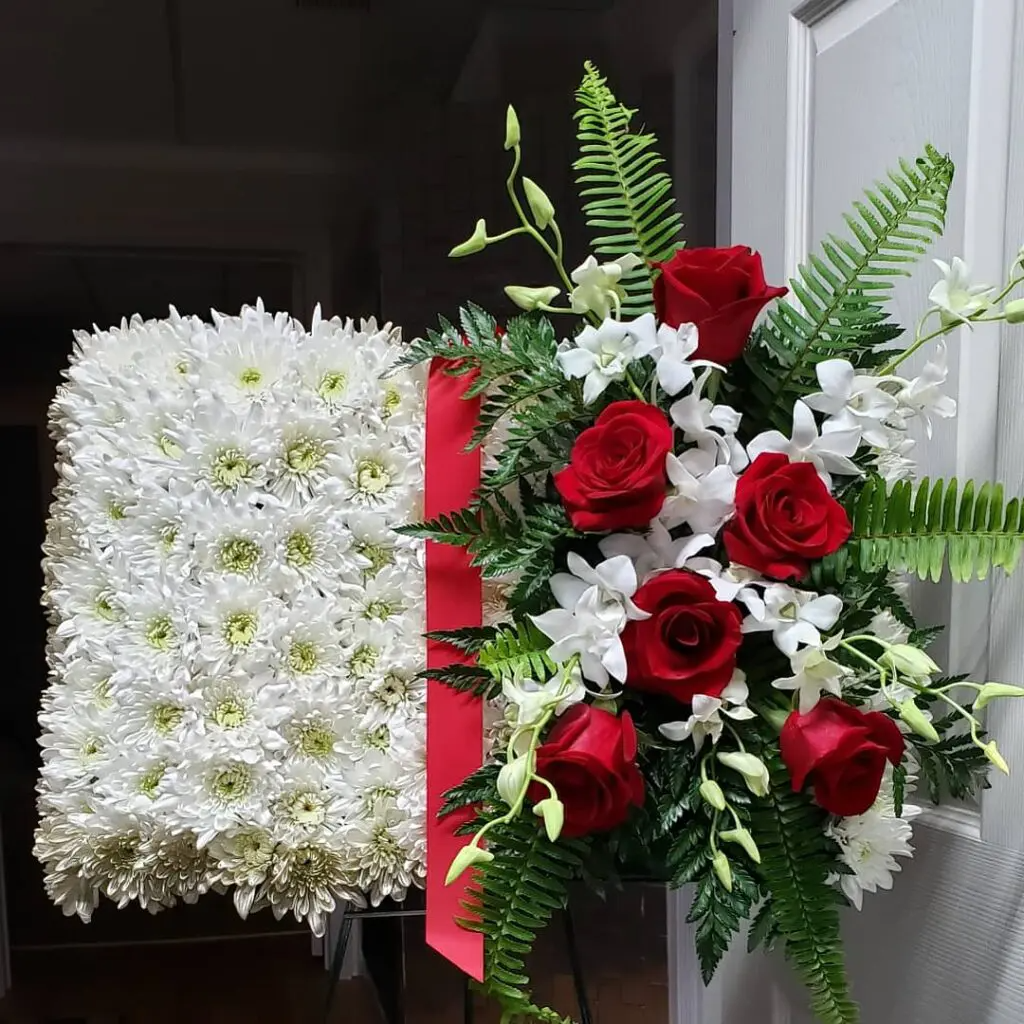 A display of white flowers with red roses and orchids
